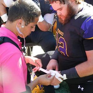 Athletic Training student puts bandage on football players hand