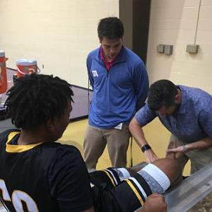 Athletic Training student puts bandage on basketball player's ankle