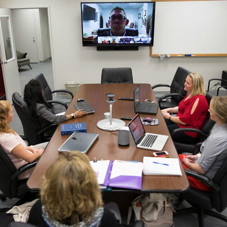 Professor delivering lecture via skype to students in a conference room