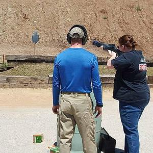 A criminal justice student fires a shotgun at a gun range.