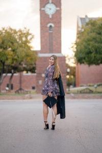 穿着毕业礼服的艾米丽Uhl站在校园的钟楼前.